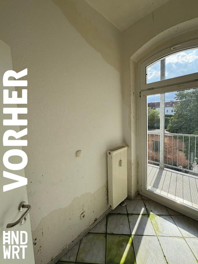 Raum mit Wasserschaden, verschmutzte Bodenfliesen, Feuchtigkeitsflecken an weißer Wand, Heizkörper und Balkontür