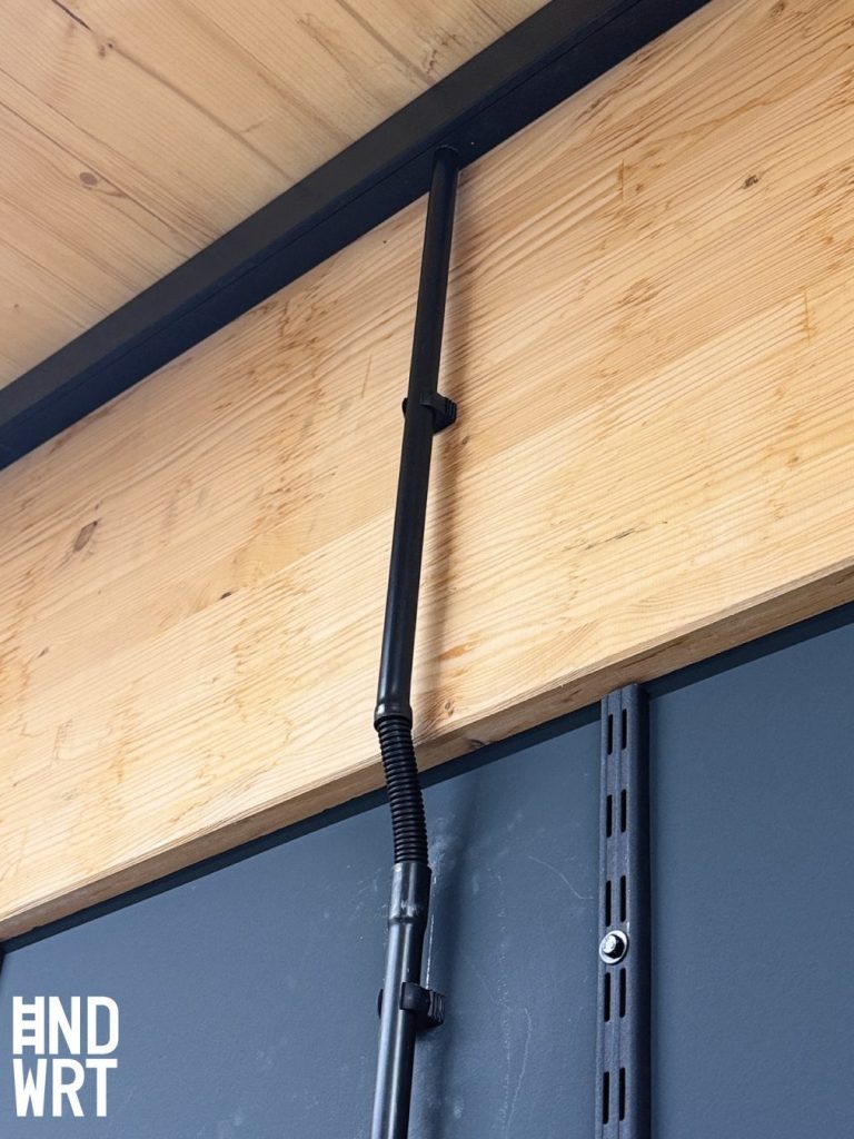 Sichtbare Holzbalkendecke mit schwarzem Stahlträger und schwarzem Kabelkanal an dunkelgrauer Wand