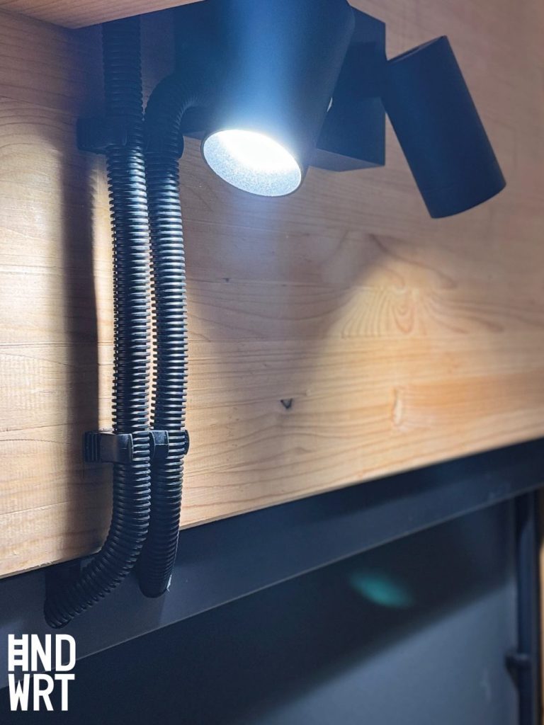 Schwarze Kabelkanäle und Strahler an Holzwand montiert, Elektroinstallation im Innenausbau