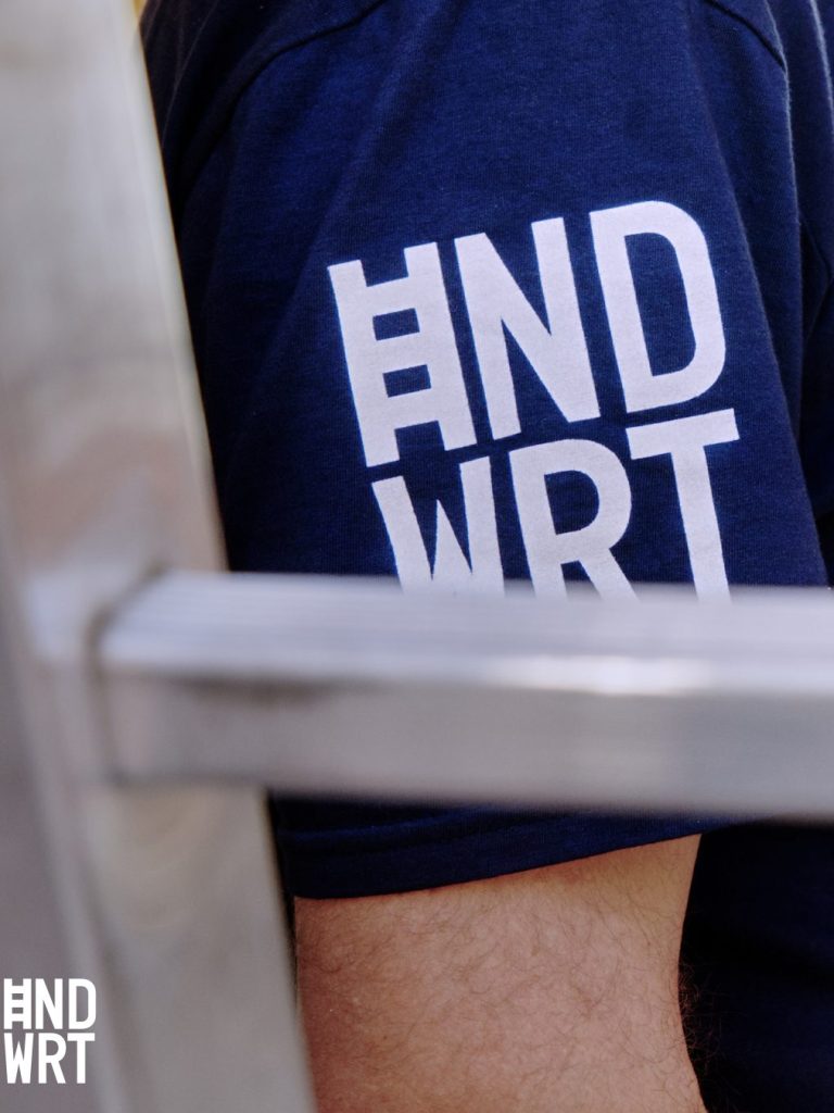 Das Bild zeigt einen marineblau gekleideten Arm mit einem Aufdruck "HNDWRT".