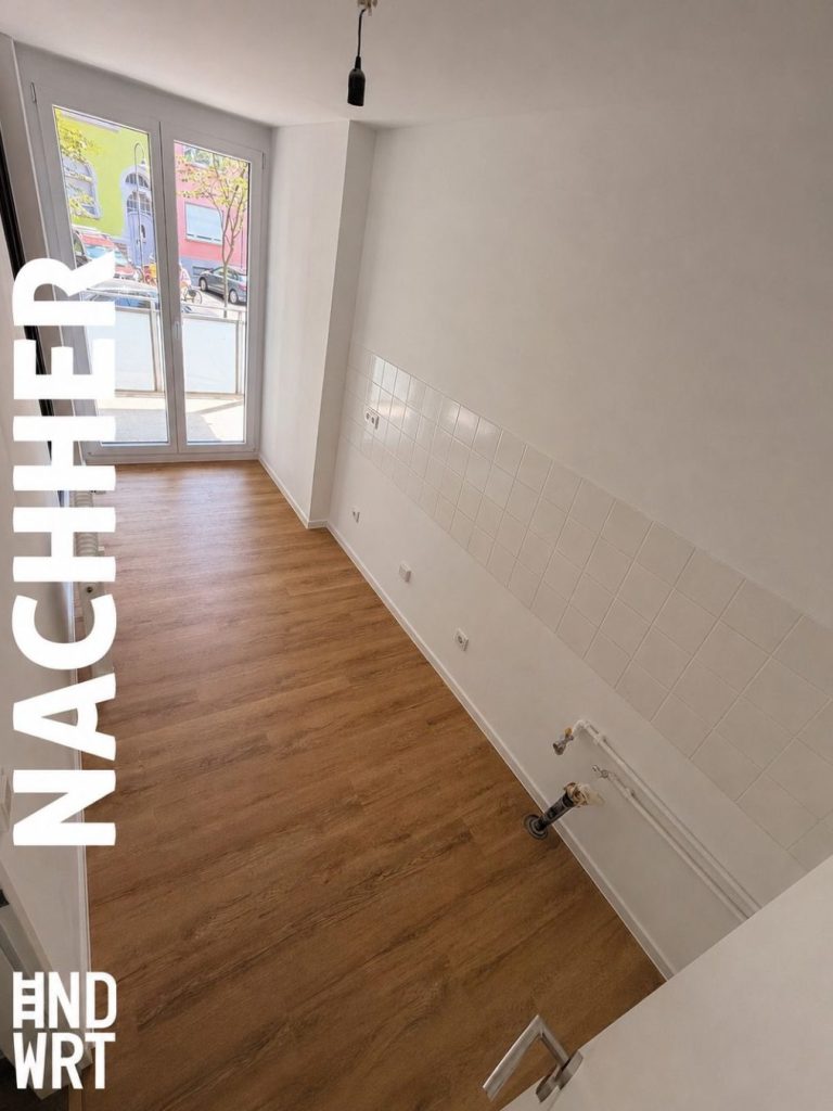 Sanierter Wohnraum mit Laminatboden, weißen Wänden, weißem Fliesenspiegel und Wasseranschlüssen für Küchenzeile