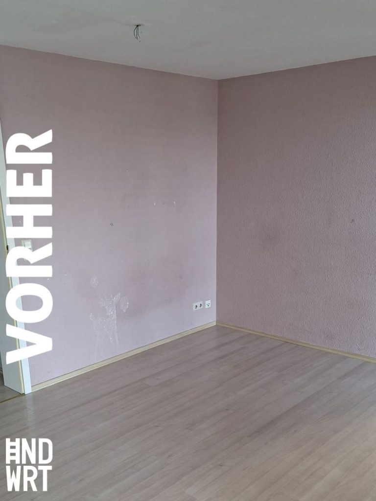 Leerer Raum mit rosa gestrichenen Wänden, weißer Decke und grauem Laminatboden, Steckdosen an der Wand