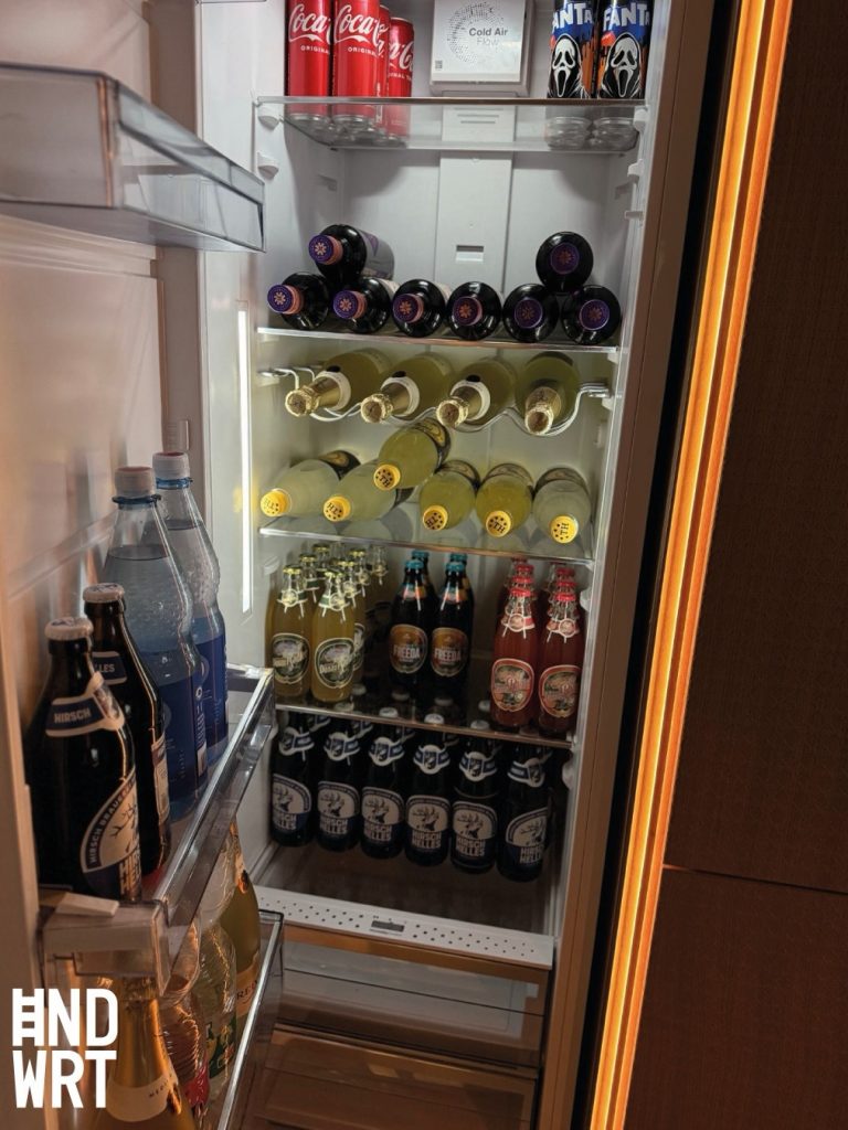 Einbaukühlschrank mit Glasablagen, gefüllt mit Getränkedosen, Weinflaschen und Bierflaschen